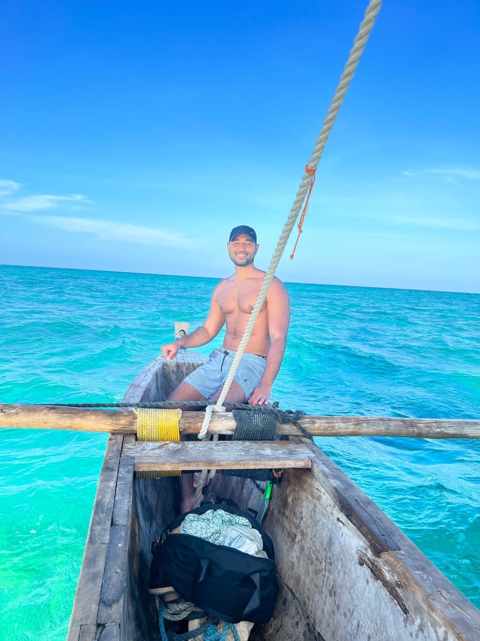 Nabil, der Gründer hinter Zanzibar Tours, auf einem Dhow-Boot über dem türkisen Wasser von Sansibar